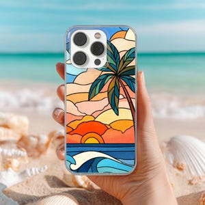 May include: Clear phone case featuring a colorful stained-glass design of a tropical sunset with a palm tree, ocean waves, and a setting sun. The case is held against a blurred beach background with seashells.