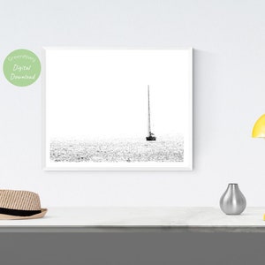 K&ouml;nnte beinhalten: Schwarz-Wei&szlig;-Druck eines Segelboots auf dem Wasser. Das Kunstwerk ist minimalistisch, mit dem Boot und seinem Mast in der Mitte vor einem hellen Hintergrund. Das Bild ist ein digitaler Download.