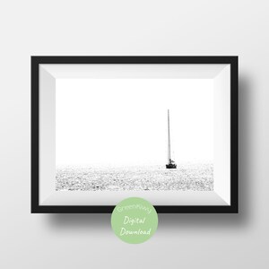 K&ouml;nnte beinhalten: Schwarz-Wei&szlig;-Druck in einem Rahmen mit einem Segelboot auf dem Wasser. Das Boot befindet sich in der Mitte des Bildes, der Mast ragt nach oben. Das Wasser ist strukturiert und schimmert. Der Rahmen ist schwarz.