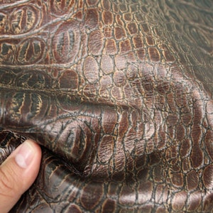 Op de afbeelding: Close-up van bruin kunstleer met een krokodil-reli&euml;fpatroon.
