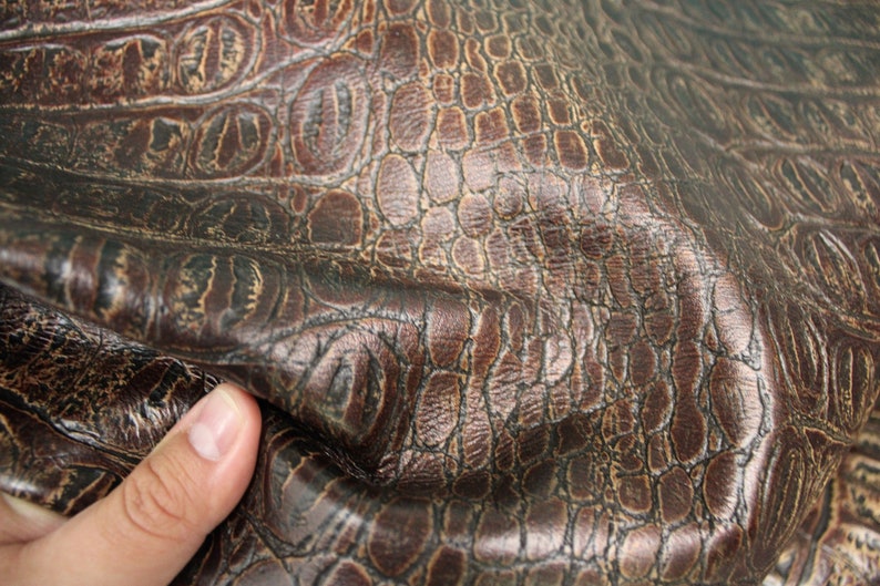 Op de afbeelding: Close-up van bruin kunstleer met een krokodil-reli&euml;fpatroon.