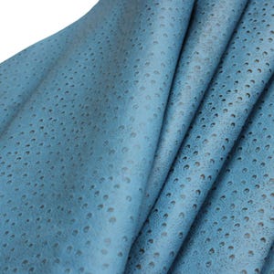 May include: Close-up of a folded piece of blue leather with a textured, dotted pattern. The leather has a soft, matte finish and a slight sheen. The color is a muted, sky blue, with darker spots creating depth and visual interest. The material appears supple and pliable.