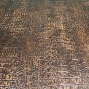 Op de afbeelding: Close-up van een bruine kunstlederen textuur met een krokodilleerpatroon.