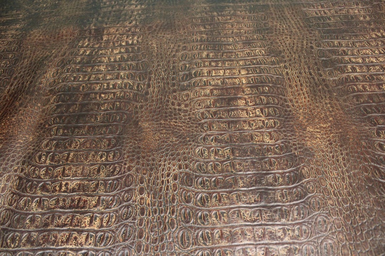 Op de afbeelding: Close-up van een bruine kunstlederen textuur met een krokodilleerpatroon.