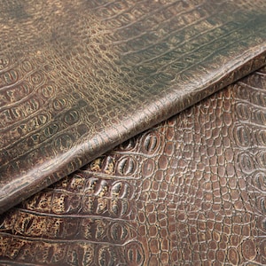 Op de afbeelding: Close-up van bruin kunstleer met een krokodil-reli&euml;fpatroon.