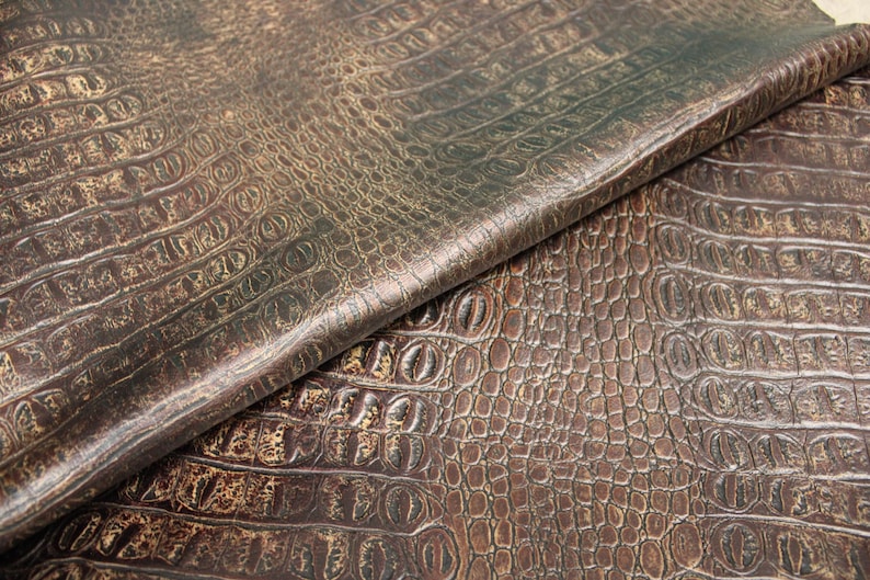 Op de afbeelding: Close-up van bruin kunstleer met een krokodil-reli&euml;fpatroon.