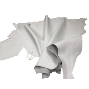 May include: A white leather hide, folded and displayed on a white background.