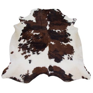 May include: A brown and white cowhide rug with a natural, spotted pattern. The rug is soft and fluffy, and would add a touch of rustic charm to any room.