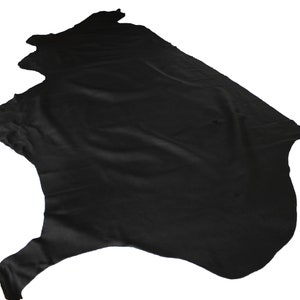 K&ouml;nnte beinhalten: Ein schwarzes Lederfell mit einer glatten, leicht faltigen Oberfl&auml;che. Das Fell ist gefaltet und &uuml;ber einem wei&szlig;en Hintergrund drapiert.