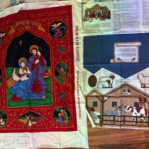 Può includere: Un pannello di tessuto a tema natalizio. Il pannello principale presenta una scena religiosa con la scritta "PEACE ON EARTH". Altri pannelli raffigurano pecore, una stalla e altre immagini religiose. Il tessuto è rosso, blu e marrone.