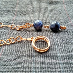 Könnte beinhalten: Eine Halskette aus Kupferkette mit zwei blauen und weißen Edelsteinperlen und einem Anhänger aus Kupferdraht.