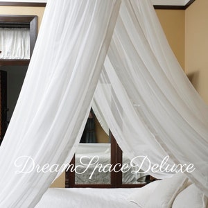 May include: White sheer canopy bed curtain hanging over a white bed with white pillows. The text "Dream Space Deluxe" is visible in the image.