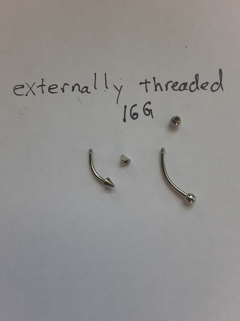 May include: Two silver externally threaded 16G body jewelry pieces. One piece has a ball end and the other has a pointed end.