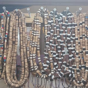 May include: A collection of wooden bead necklaces in various colors and patterns. The necklaces are made of natural wood beads and feature different shapes and sizes.
