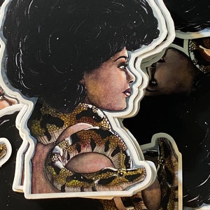 May include: A collection of stickers featuring a woman with a large afro and a snake wrapped around her shoulders. The woman is depicted in profile, with detailed facial features and a warm skin tone. The snake has a detailed pattern of brown, yellow, and black.