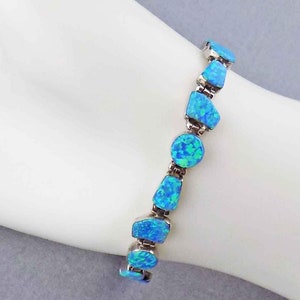 May include: A silver bracelet with blue opal stones. The bracelet is made of small, irregular shaped stones that are connected by silver links.