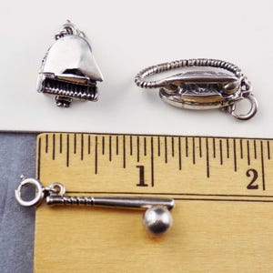 May include: Three silver charms: a piano, a vintage iron, and a baseball bat with a ball. The piano charm has a detailed keyboard. The iron charm has a looped handle. The baseball bat charm is 1 inch long.