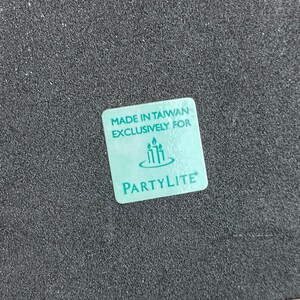 May include: A teal blue square label with the text "Made in Taiwan Exclusively for PartyLite" and a logo of three candles in a circle.