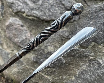 May include: Two metal shoe horns, one with a twisted design and a rounded knob on the end, and the other with a smooth, flat surface.