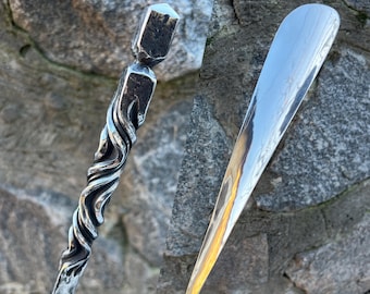 May include: Two metal shoe horns, one with a twisted design and the other with a smooth, rounded tip. Both are made of polished metal and have a reflective surface.