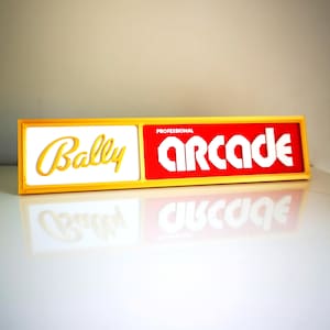 May include: A yellow and red sign with the words "Bally Professional Arcade" in white lettering.