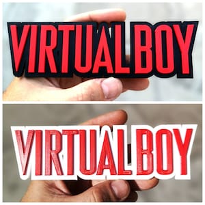 以下が含まれることがあります： 赤い文字で「VIRTUAL BOY」ロゴが3Dプリントされたものが2つあります。 上のバージョンは黒い背景に印刷され、下のバージョンは白い背景に印刷されています。