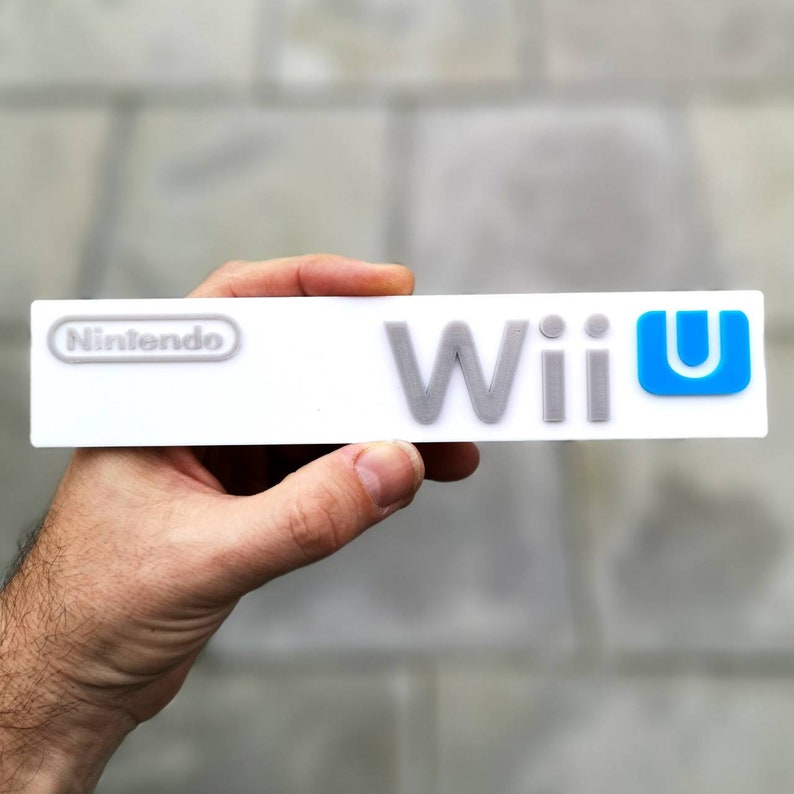 May include: A white rectangular sign with the text "Nintendo" and "Wii U" in gray lettering. The "U" in "Wii U" is blue.