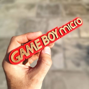 May include: A red plastic keychain with the words "GAME BOY MICRO" in gold lettering.