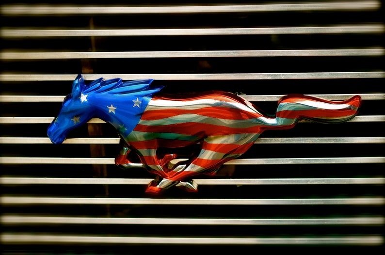 Puede incluir: Un caballo estilizado en cromo corriendo con rayas rojas y azules, que se asemeja a la bandera estadounidense, en una parrilla plateada.