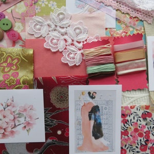 Puede incluir: Una colección de materiales de artesanía para scrapbooking y proyectos de arte mixto. Los materiales incluyen recortes de tela, encaje, cinta, botones y papel. También hay dos tarjetas con diseños florales y de inspiración japonesa.