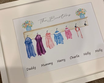May include: A white framed print with a watercolor illustration of a coat rack with six coats hanging on it. The text "The Bartons" is at the top of the print. Below the coat rack are the names "Daddy", "Mummy", "Harry", "Charlie", "Holly", and "Molly".