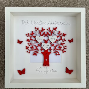 May include: A white frame with a red and white tree design. The tree has two hearts at the top with the names John and Mary. The date 4th May 1984 is written on the tree. The text "Ruby Wedding Anniversary" and "40 Years" is written on the frame.
