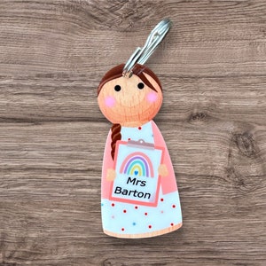 May include: A pink and white teacher keyring with a rainbow and the text "Mrs Barton".