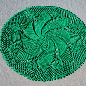 Puede incluir: Un encaje de ganchillo verde con un patrón de espiral en el centro.