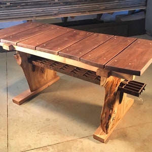 May include: A handcrafted wooden bench with a dark brown top made of planks. The bench features a light brown base with a unique, natural wood grain design. The bench is approximately 60 inches long.