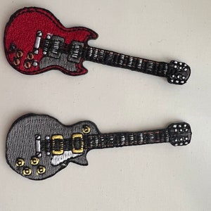 May include: Two embroidered guitar patches. One is red with a grey pickguard and black neck. The other is grey with a gold pickguard and black neck. Both have detailed stitching.