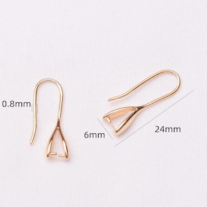 May include: Gold-colored earring hooks, 24mm long, with a 6mm wide base and a 0.8mm wire thickness. The hooks have a classic shepherd's hook design, perfect for jewelry making.