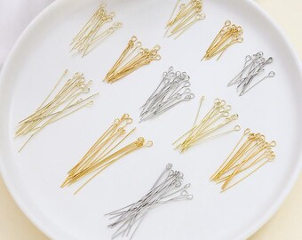 Può includere: Primo piano di perni a occhiello dorati e argentati disposti su un piatto bianco. Ogni perno ha un'asola a un'estremità e un filo dritto. Questi materiali sono ideali per la creazione di gioielli.