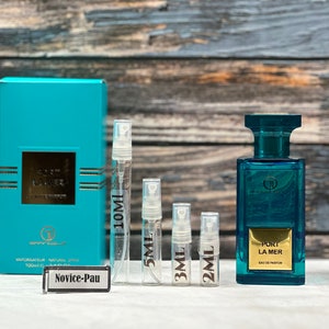 May include: A turquoise blue box with gold lettering that reads "Port La Mer" and a smaller box with the text "Novice-Pau". There are five clear glass perfume sample bottles with black lettering that reads "10 ml", "5 ml", "3 ml", and "2 ml".  A larger turquoise blue bottle with gold lettering that reads "Port La Mer" Eau de Parfum.