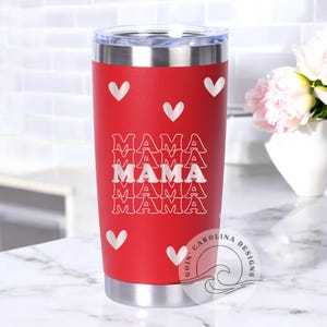 May include: Red stainless steel tumbler with a white design of the word "MAMA" repeated five times and white hearts. The tumbler has a silver lid and a white logo on the bottom that says "Goin' Carolina Designs".