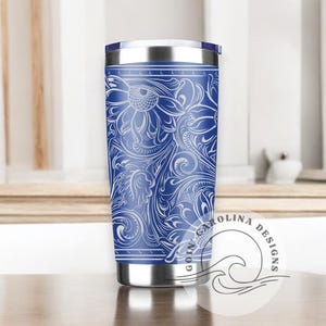 Peut inclure: Un gobelet isotherme en acier inoxydable bleu avec un motif floral blanc. Le gobelet est dot&eacute; d'un couvercle et est parfait pour garder les boissons froides ou chaudes.