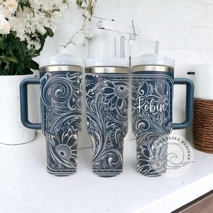 Peut inclure: Trois gobelets en acier inoxydable avec un motif floral bleu et blanc. Les gobelets ont un couvercle avec une paille et une poign&eacute;e. Les gobelets sont personnalis&eacute;s avec le nom "Robin".