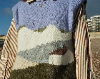 May include: A purple, white, brown and green knitted vest with a landscape design. The vest is sleeveless and has a ribbed texture.