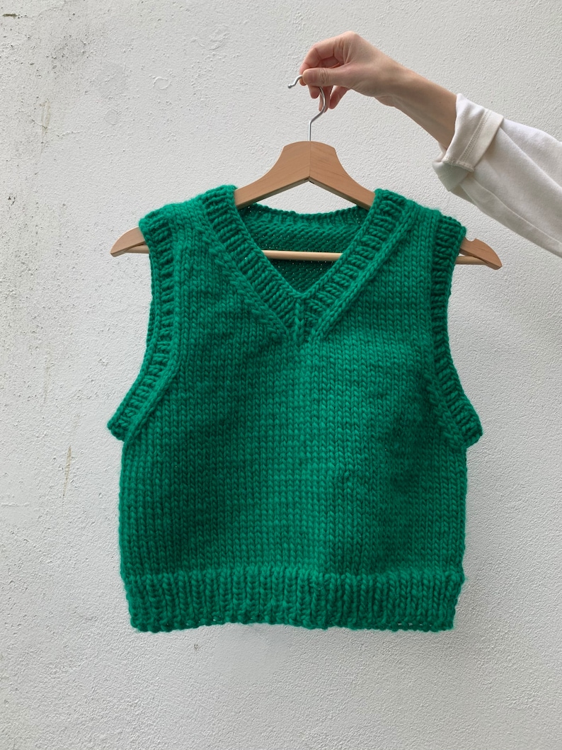 Puede incluir: Un chaleco de punto verde sin mangas con cuello en V.