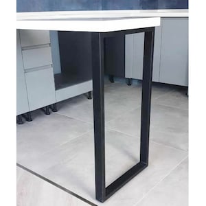 May include: A black metal table leg with a square base. The leg is attached to a white table top.