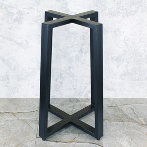 Puede incluir: Una base de mesa de metal negro con un soporte en forma de X en la parte inferior y una parte superior cuadrada. Las patas son rectangulares y se conectan a la parte superior, formando un marco resistente. La base está diseñada para una mesa.
