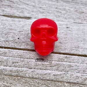 Peut inclure: Une figurine de cr&acirc;ne en plastique rouge vif.