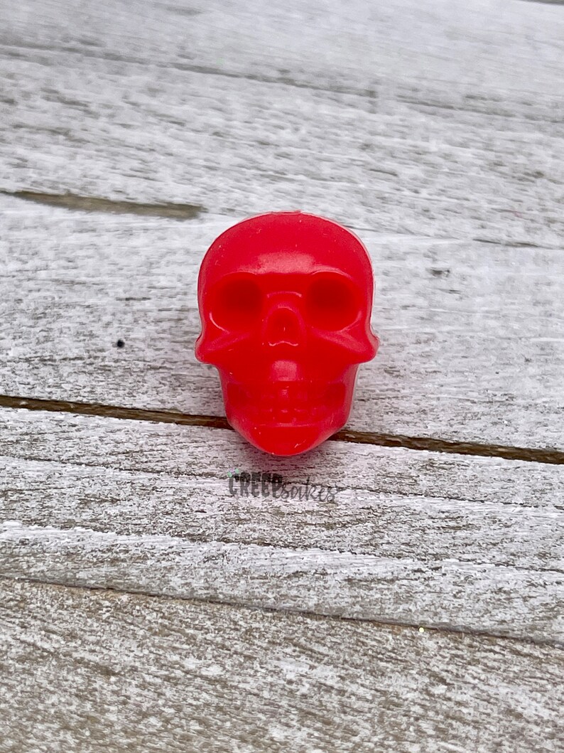 Peut inclure: Une figurine de cr&acirc;ne en plastique rouge vif.