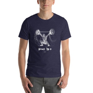 May include: A navy blue t-shirt with a white graphic of a weightlifter lifting a barbell. The graphic is made up of small white dots. The text "lifting heavy" is printed below the graphic.