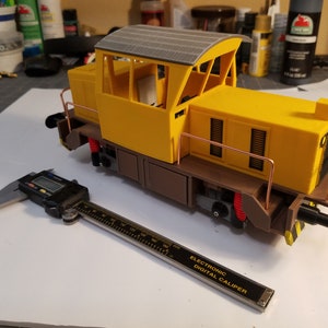 Könnte beinhalten: Eine gelbe und braune Spielzeug-Lokomotive mit einem grauen Dach und einer digitalen Schieblehre, die 15,24 cm misst.